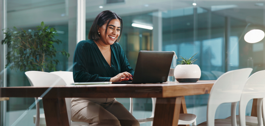 A happy woman typing at her laptop